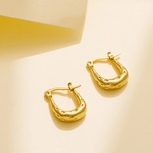 Macro view of gold U-shaped earrings featuring a hammered texture and polished metal finish