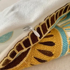 Close-up detail shot of embroidered pillow cover with 3d towel embroidery texture and zipper.