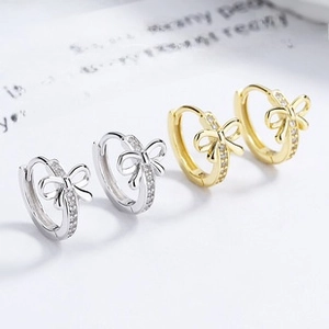 Detailed view of silver and gold U-shaped bow earrings with sparkling cubic zirconia pavé