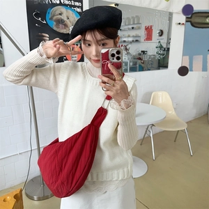 Macro view of red nylon dumpling bag with wide shoulder strap and metal ring detail