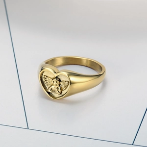 Macro shot of gold stainless steel heart ring with embossed angel relief detail