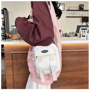 Vista laterale di una borsa a tracolla bianca in nylon con fibbie e etichetta moda