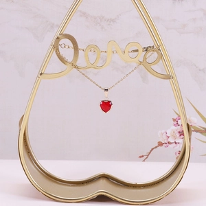 Detail of a red heart crystal pendant with gold plating on an elegant heart display stand