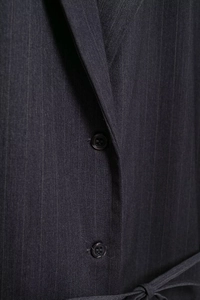 Detailed macro view of dark grey pinstripe blazer fabric with black buttons and belt