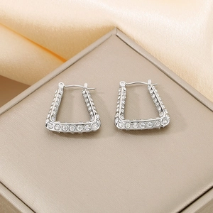 Detail of silver U-shaped earrings with micro-paved diamonds on a textured display box