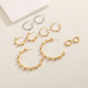 Close-up of geometric gold and silver hoop earrings with vibrant colorful gemstones