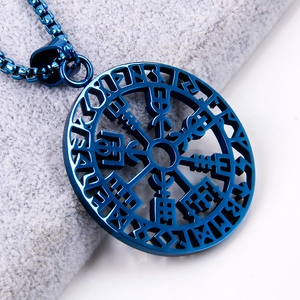Macro shot of blue Viking compass pendant with ancient runes on grey velvet background