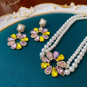 Detail von Vintage Blumenohrringen und doppelter Perlenkette auf einem Samttablett