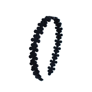 Close-up of black matte acrylic headband with 3D daisy flower embossed texture