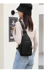 Detailed view of black nylon chest bag with headphone port and smooth zippers