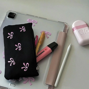 Astuccio in tela nera con ricamo fiocco rosa e cancelleria in una scena da scrivania