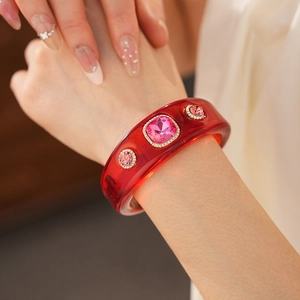 Close-up of red resin vintage bangle with pink crystals and shimmering rhinestone trim