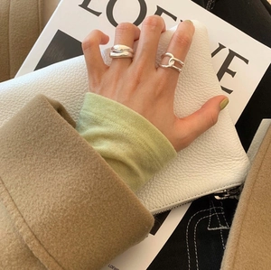 Detail of chunky 925 sterling silver irregular rings on model fingers in minimalist style
