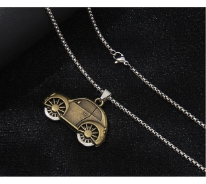 Detail of vintage bronze car pendant with a silver bead chain on a dark textured surface