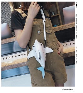 Detailed view of creative white shark crossbody bag with light blue fins on a model