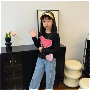 Detail of pink heart-shaped chain bag and bow applique on girl's casual outfit