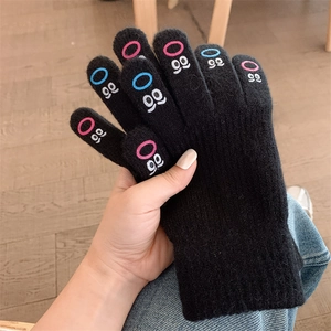 Close-up detail of black knit touchscreen gloves featuring cute embroidered eye patterns on fingers.