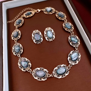 Macro detail of vintage gold jewelry set with oval blue-grey resin stones in a display box