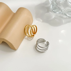 Close-up of minimalist layered stainless steel open rings with braided texture details