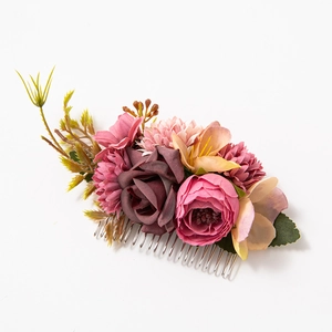 Detail of fabric floral hair comb with pink, wine red, and champagne flowers on white back