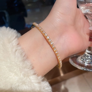 Close-up of elegant 18K gold plated open bangle with sparkling cubic zirconia on female wrist