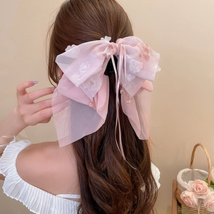 Dettaglio della clip per capelli a fiocco in organza rosa con fiori 3D e lunghe nappe