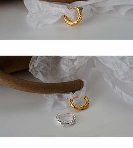 Detailed close-up of textured gold and silver hoop earrings with a hammered finish surface