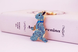 Close-up of a gold kangaroo pendant with sky blue rhinestones on a pink book cover