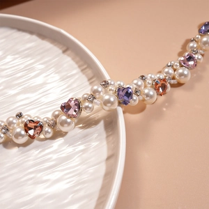 Close-up of pearl necklace with colorful heart-shaped gems and sparkling rhinestones