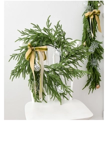Detail of Norfolk Christmas wreath with velvet bow and clear ornaments on a white chair