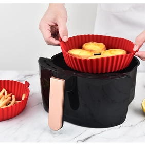 Detail of red silicone air fryer liner being placed inside a black air fryer basket