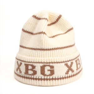 Detailed knit texture of a beige and brown striped winter beanie with XBG lettering