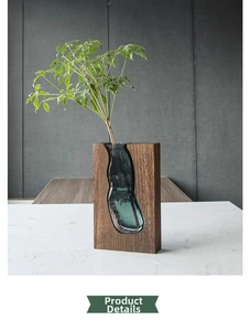 Detailed view of dark wood base and emerald green glass vase in minimalist zen style