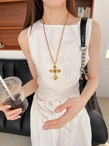 Détail du collier pendentif croix avec pierres rouges porté par un mannequin en douceur