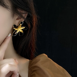 Close-up of a model wearing black and gold floral earrings with enamel finish detail
