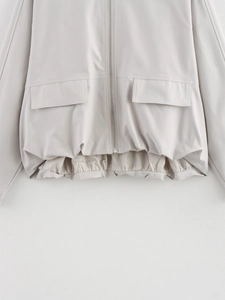 Detail of light grey jacket featuring elasticated hem and large symmetrical flap pockets
