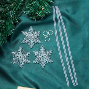 Close-up of transparent acrylic snowflake ornaments set on dark green silk background