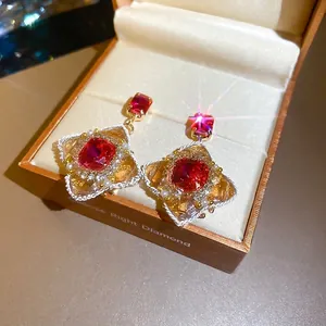 Vintage gold earrings with square red gemstone and pearl accents in a brown jewelry box