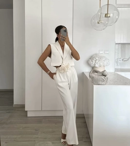 Detailed view of white sleeveless vest set with a decorative floral accent and wide-leg pants