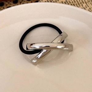 Detail of black elastic hair tie featuring a polished silver X-shaped metal geometric accent