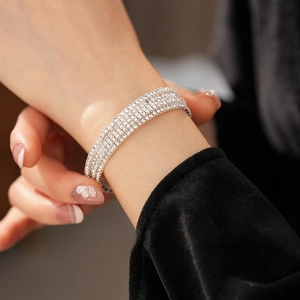 Detail of four-layer silver crystal stretch bracelet on wrist with black velvet sleeve