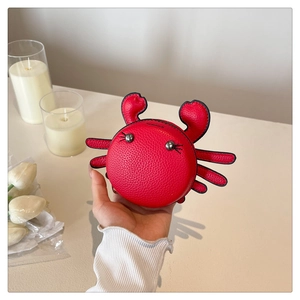 Detail of red crab-shaped mini bag in litchi leather held by hand with cute rivet eyes