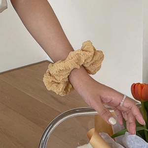 Detailansicht eines beigefarbenen Haargummis mit Blasenstruktur als Handgelenk-Accessoire