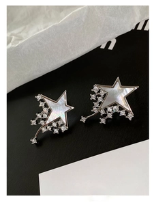 Detail of star-shaped earrings with mother of pearl and cubic zirconia stones