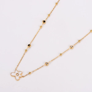 Detail of gold necklace featuring white mother of pearl flower pendant and pearl center