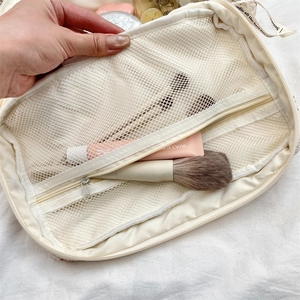 Macro view showing multi-layer mesh pockets and large capacity of the beige makeup bag