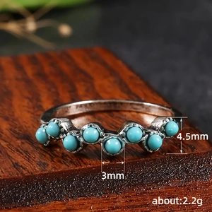 Bague vintage en argent oxydé avec sept perles turquoise sur un socle en bois