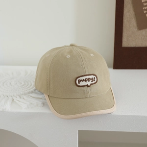 Detail of khaki kids baseball cap featuring puppy embroidery and light-colored piping edge
