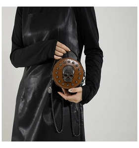 Detail of vintage brown leather bag with metallic skull and rivets on model in black leather