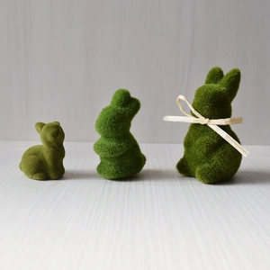 Three green flocking moss rabbit statues for Easter home decor on a wooden surface